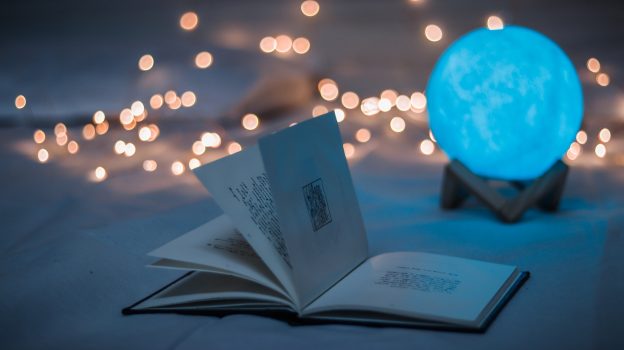 magic ball with open book and string lights