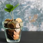 Glass of coins with plant